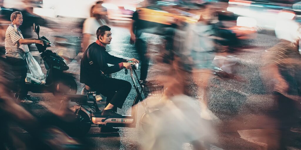 stationary man on a scooter with a crowd moving around him