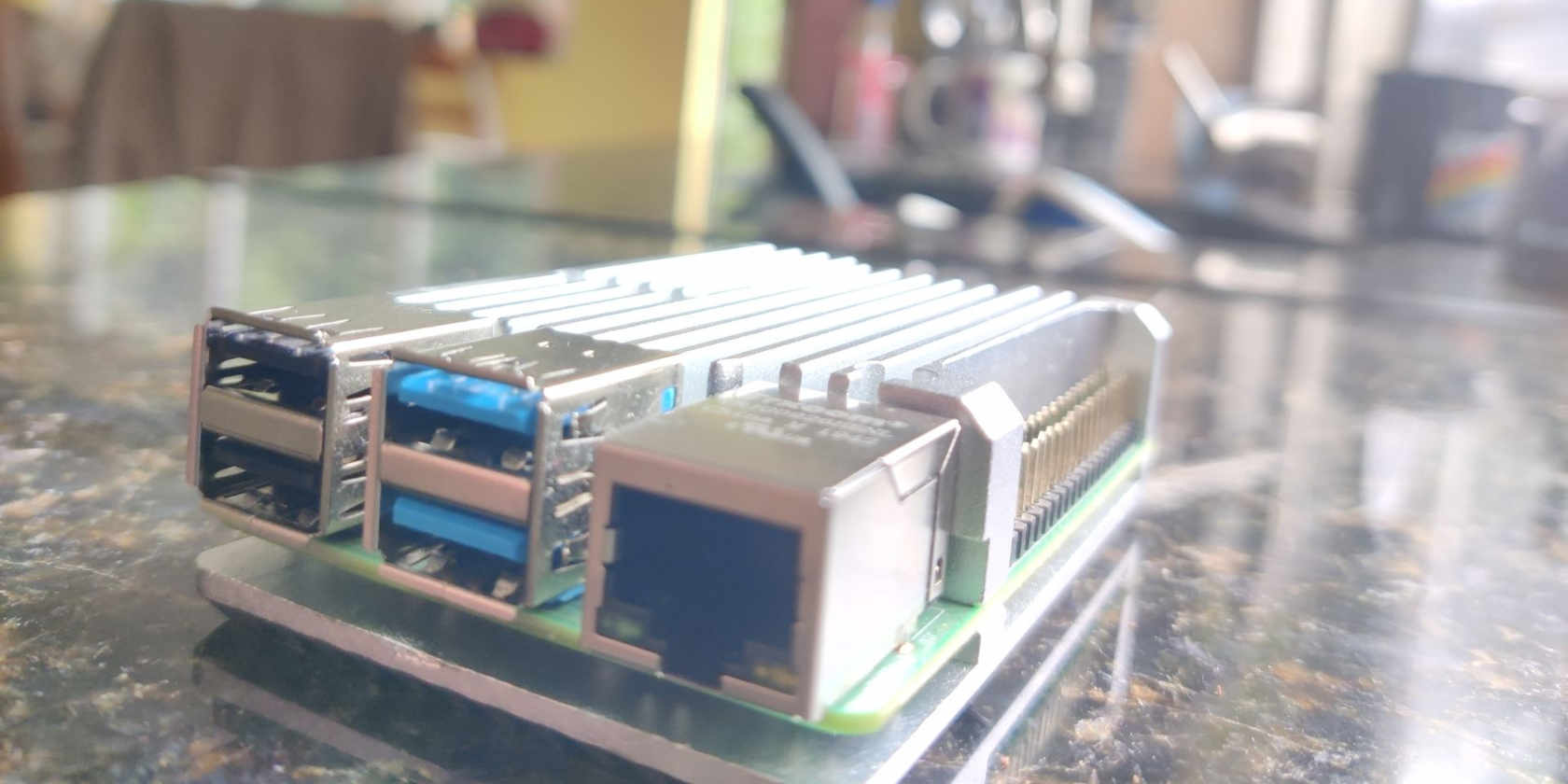 A raspberry Pi in metallic silver passive cooled cased on a granite kitchen worktop