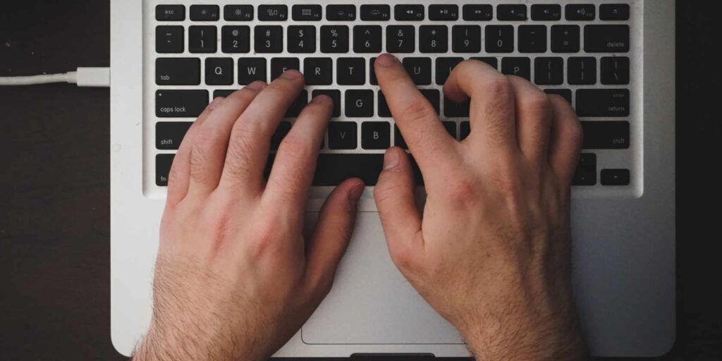 hands typing on a laptop keyboard