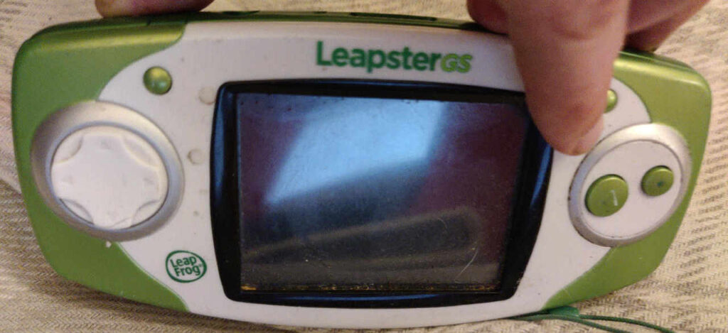 A grimy leapster GS with fingers positioned in an awkward way