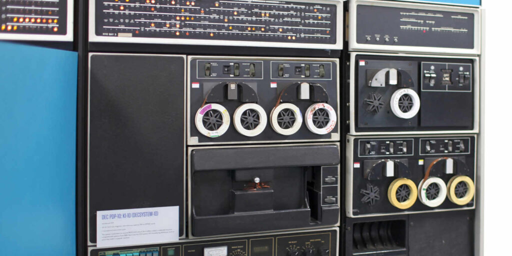 a wall-sized computer with blinking lights and huge tape reels