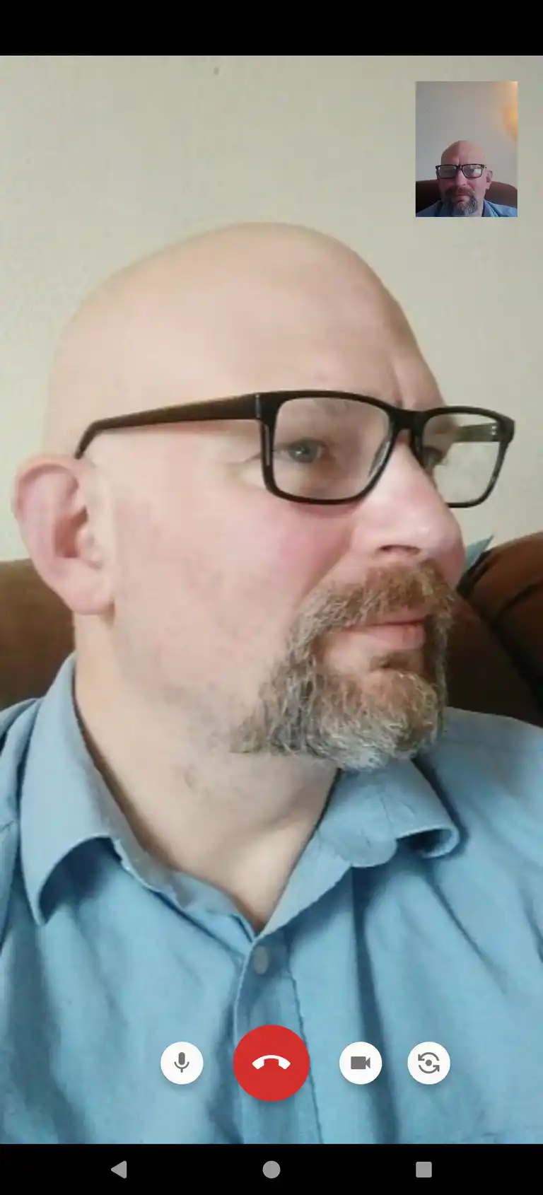 A shaven-headed man conducting a video call with himself