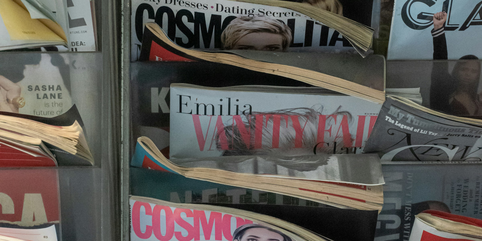 A magazine rack with copies of cosmo, vanity fair, and glamour