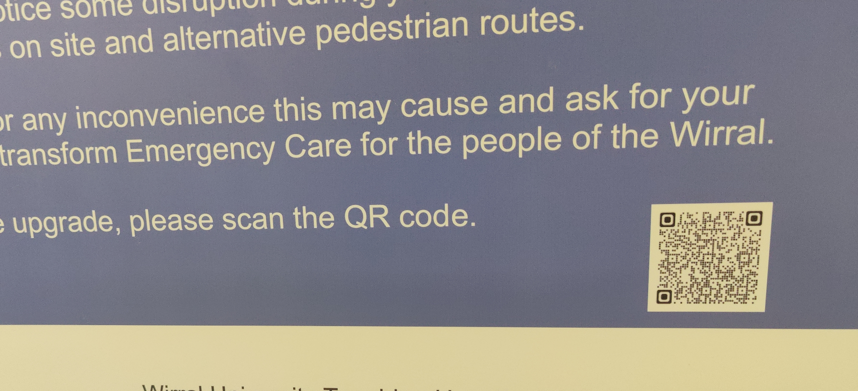 A blue and white sign in an NHS hospital. It directs visitors to scan a qr code