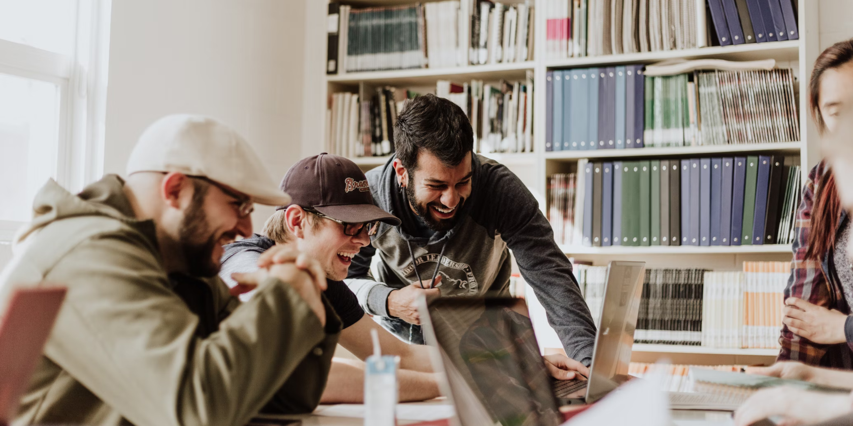 A group of people in a library - looking at laptops and laughing